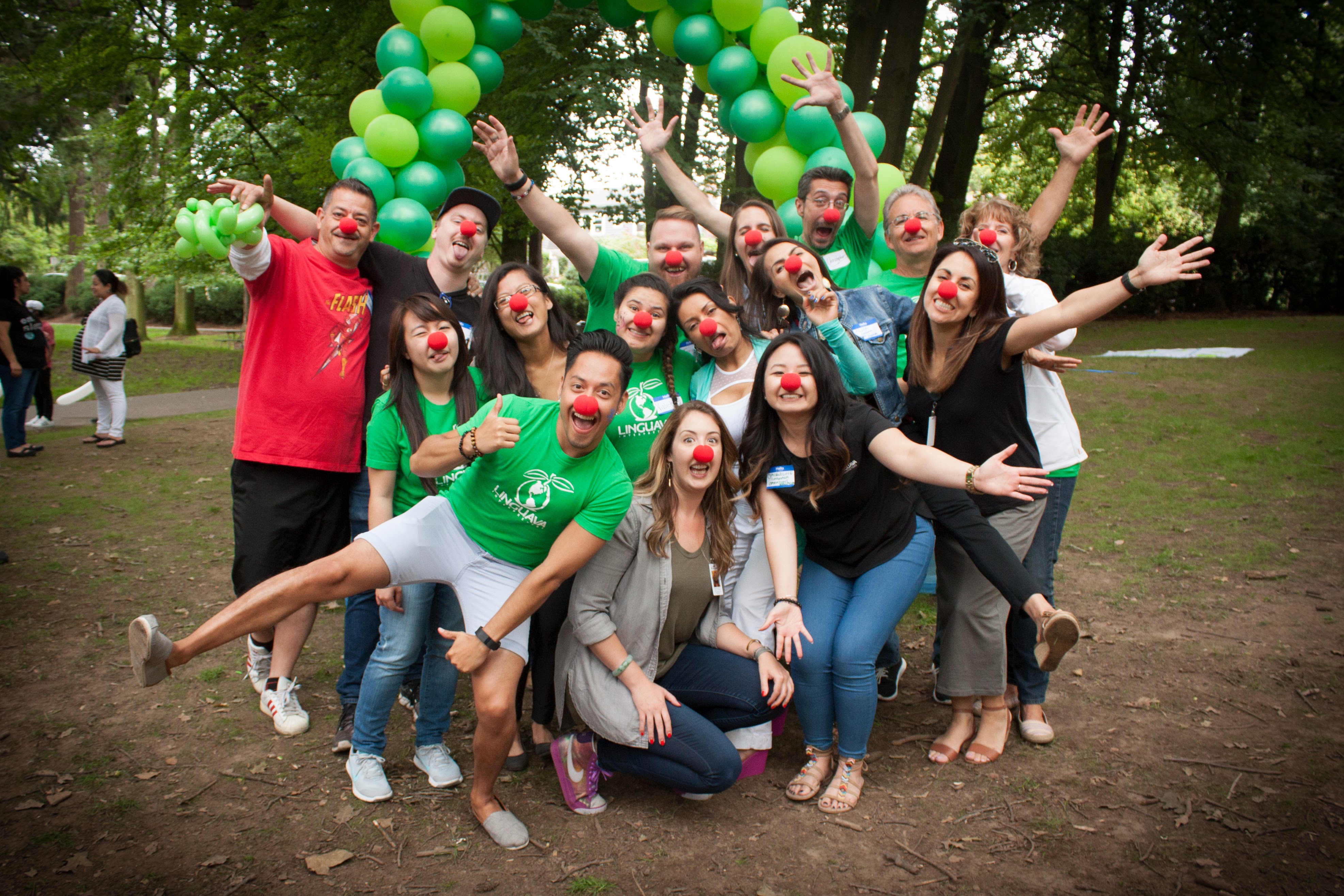 linguava interpreters staff wearing red noses under green balloon arch