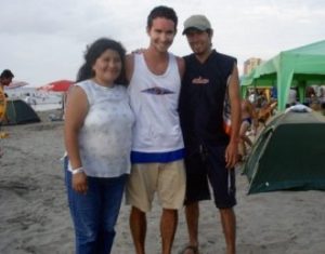 David smiles while standing between two people at a beach
