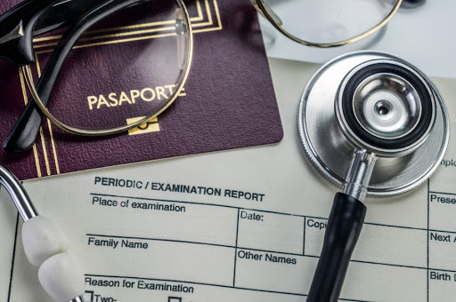 group of items including passport, stethoscope, glasses and paper reading examination report