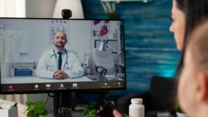 close up of mother and daughter in a room talking to a doctor on a large video screen showing video remote interpretation at Linguava