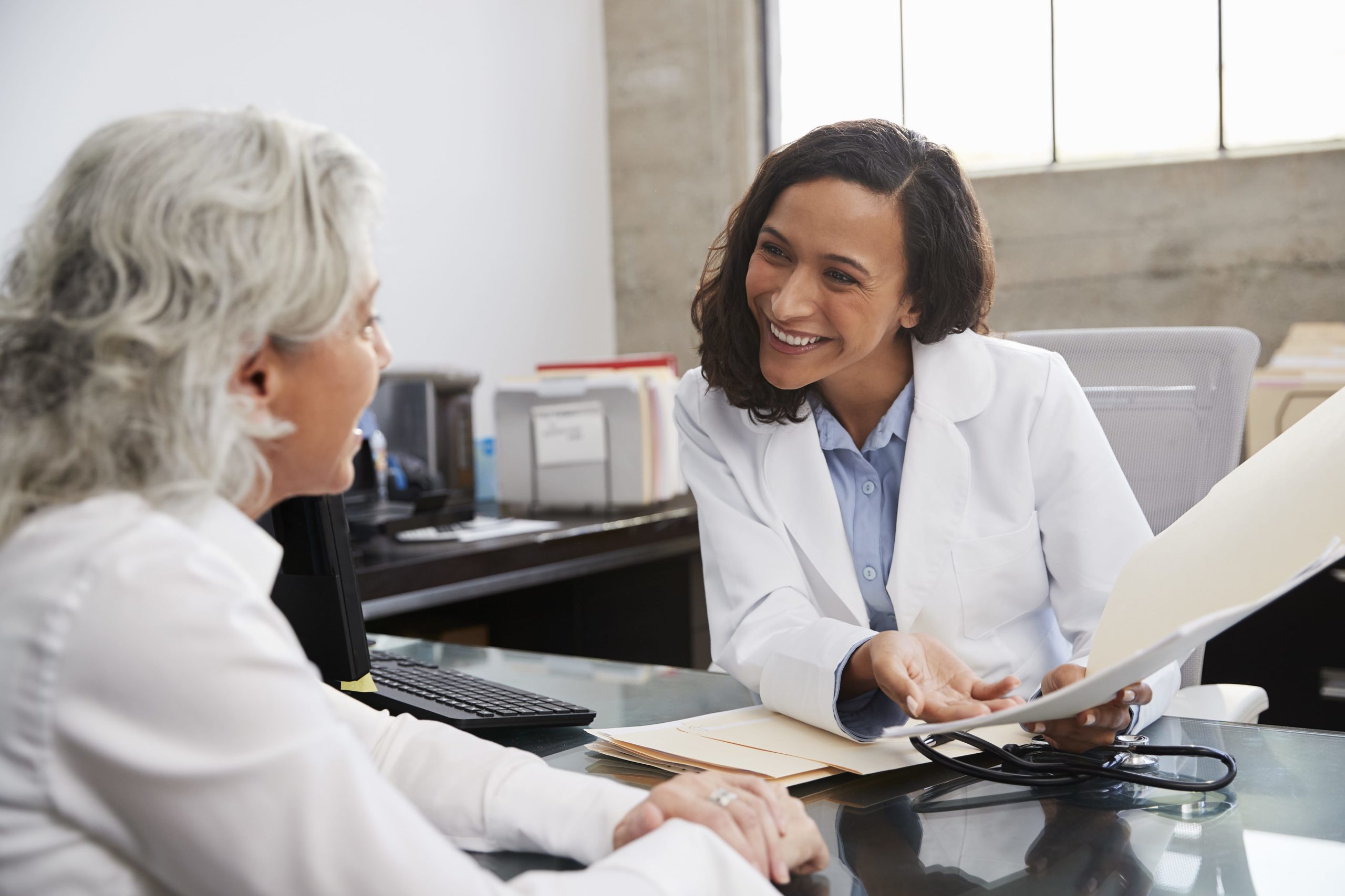 smiling female doctor sitting in consultation with senior patient for onsite interpretation