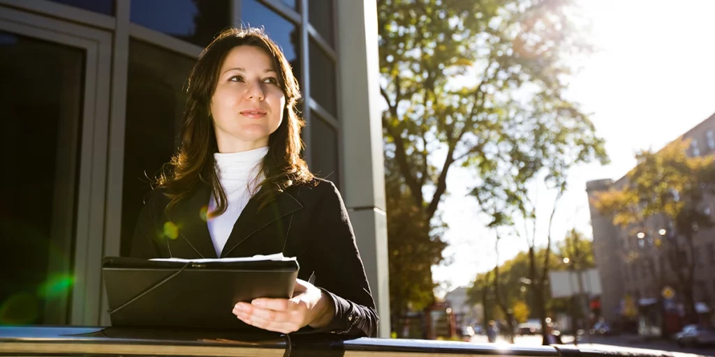 dark haired woman outside holding a black folder as a professional translator