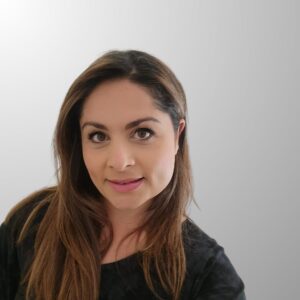 headshot of valeria mcnulty wearing a black shirt and long brown hair in front of a gray background