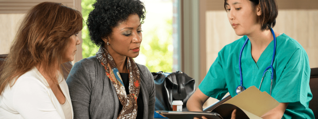 female medical worker showing female patient and family member or interpreter translated documents