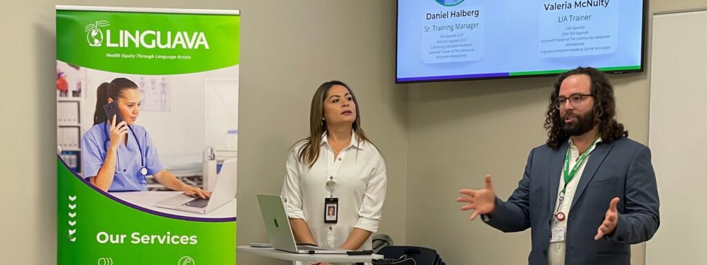 valeria mcnulty, linguava interpreter trainer, and daniel halberg, director of training and client success, standing next to a linguava banner talking to an audience about interpreting in oregon
